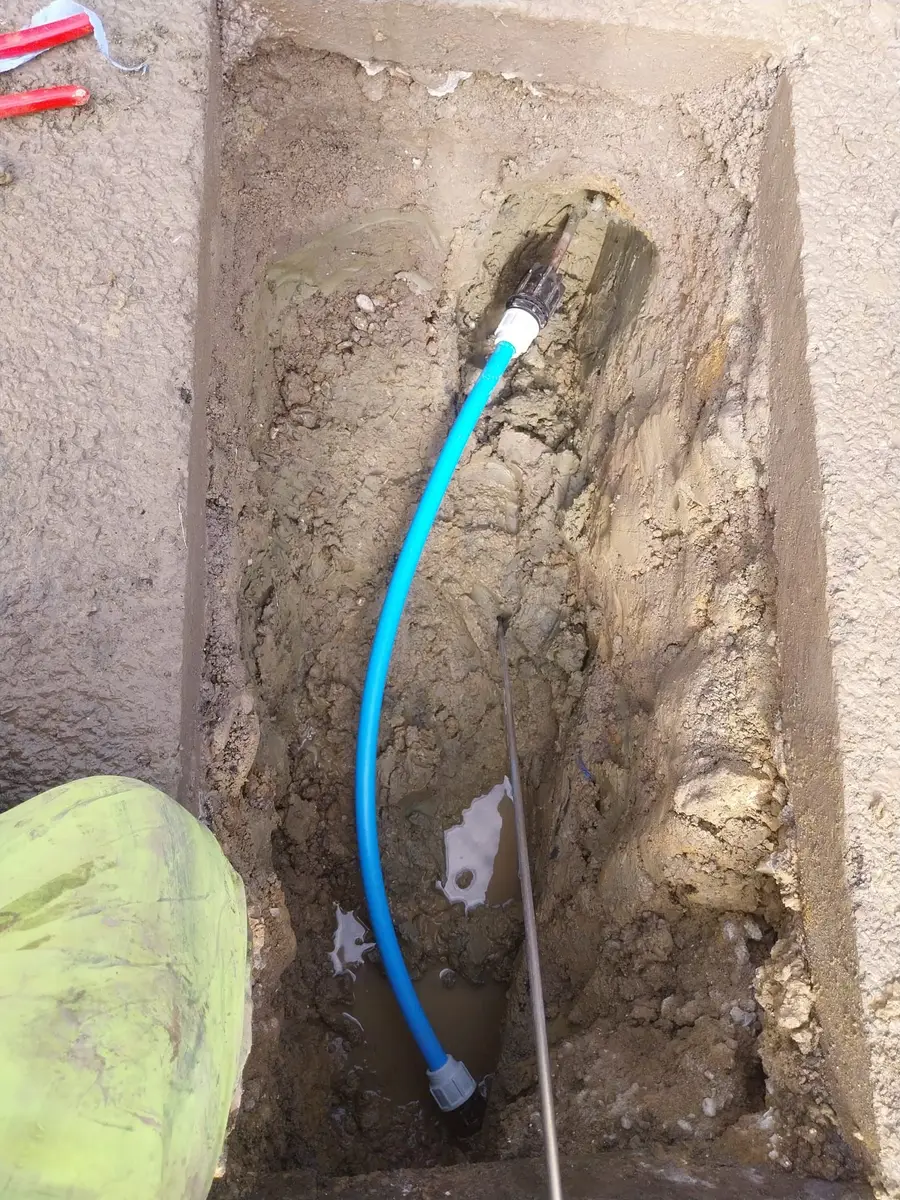 New blue MDPE supply pipe installed in a narrow excavation
