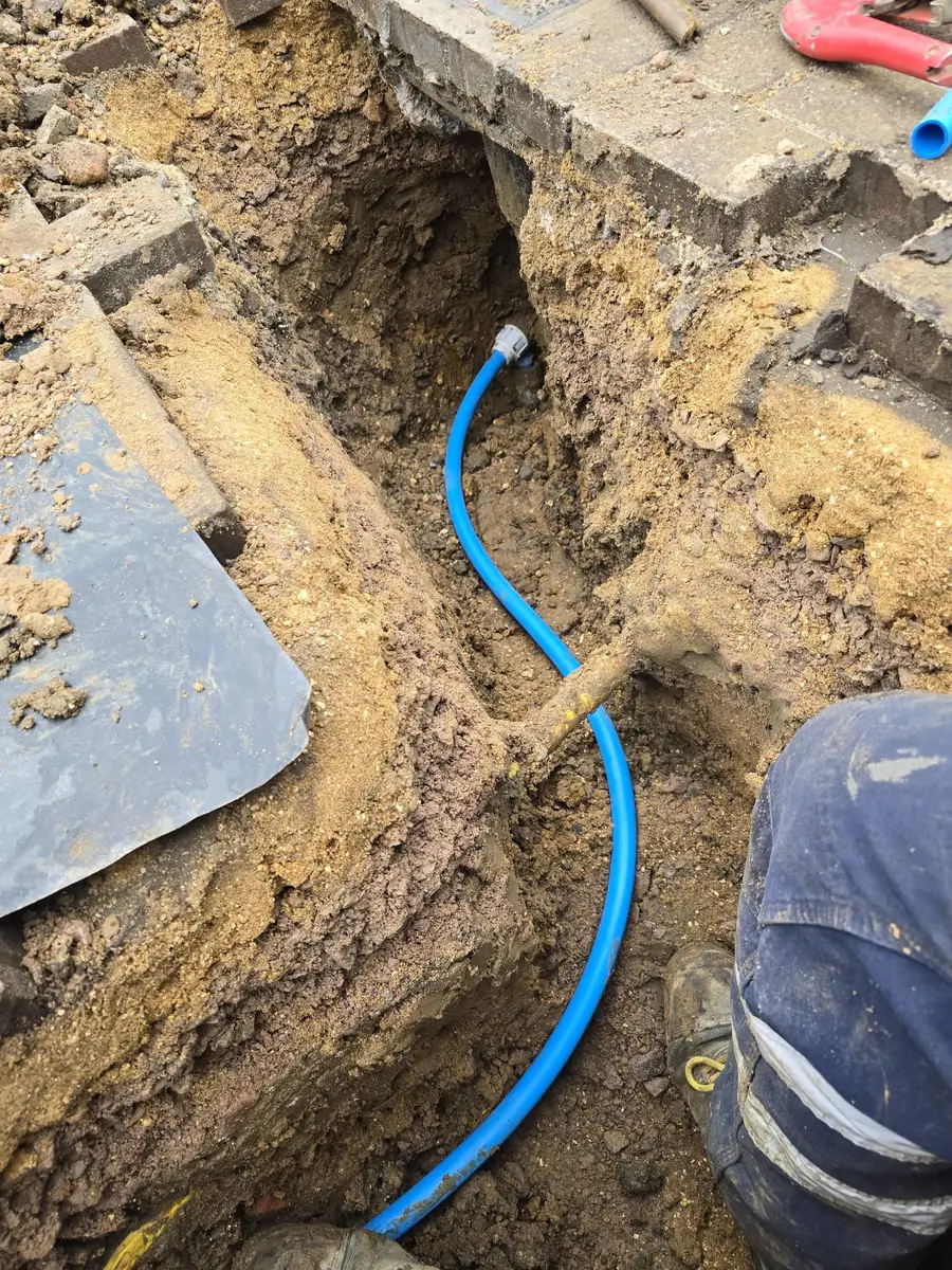 Private water supply pipe being renewed from a trench across a driveway