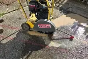 Floor saw cutting the line for the new water main across hardstanding